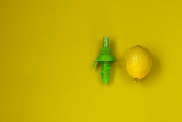 Fresco limón jugoso maduro sobre un fondo de color oliva. Boquilla de pulverización verde para cítricos. Vista superior con espacio de copia. Posición horizontal. Copiar espacio. - Foto, Imagen