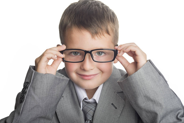 Portret dziecka ubranego w garnitur biznesowy i okulary jako biznesmen. Twarz mądrego chłopca w okularach i garniturze dla dorosłych na białym tle. - Zdjęcie, obraz