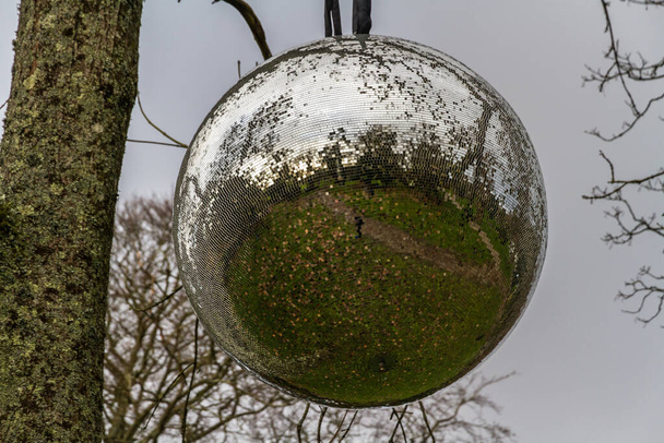 Grote spiegelbal hangend aan een boom, landschap. - Foto, afbeelding