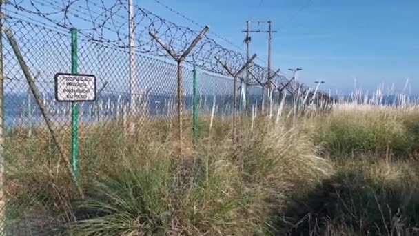 Alter und rostiger Zaun versperrt den Weg zu den Ruinen eines stillgelegten Atomkraftwerks - Filmmaterial, Video