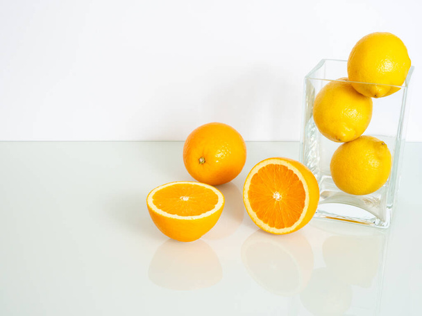 świeże żółte pomarańcze i cytryny w szklanym wazonie na białym tle - Zdjęcie, obraz