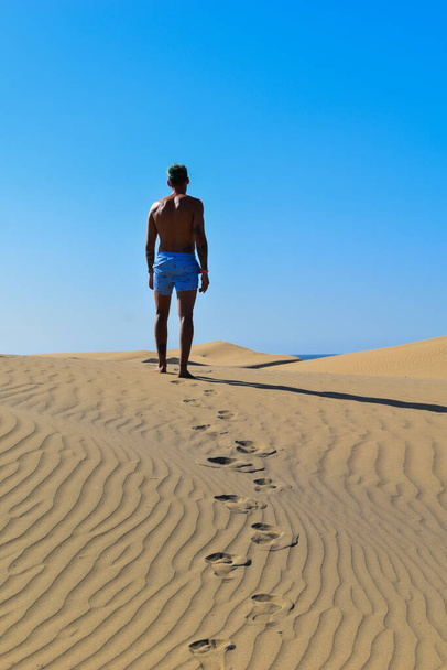 Muž kráčí v plavkách pouští pod sluncem. - Fotografie, Obrázek