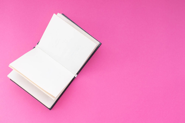 Ανοιχτό χάρτινο βιβλίο με λευκές σελίδες σε ροζ φόντο. Με χώρο αντιγραφής. - Φωτογραφία, εικόνα