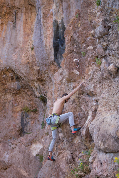 Un homme fort grimpe une falaise. L'alpiniste surmonte une route d'escalade difficile sur un terrain naturel. Escalade en Turquie. Belle roche orange. - Photo, image