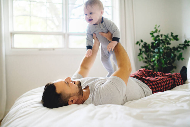 A Father with cute baby son on bed at home - Photo, image