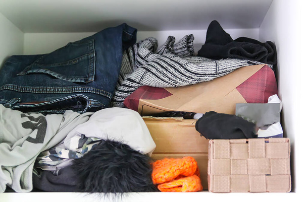 Home wardrobe with different clothes. Small space organization. Disorder. Vertical storage box - Photo, Image