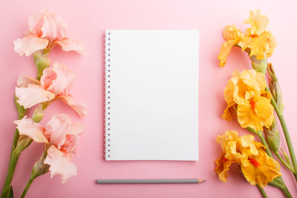 Flores de íris rosa e laranja com notebook sobre fundo rosa pastel. Morninig, primavera, composição de moda. Deitado plano, vista superior. - Foto, Imagem