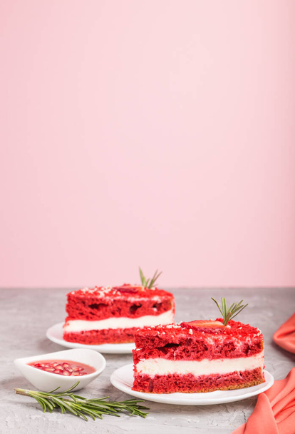 ミルククリームとストロベリーの自家製レッドベルベットケーキは、グレーとピンクの背景に赤いテキスタイル。サイドビュー、コピースペース、選択的フォーカス. - 写真・画像