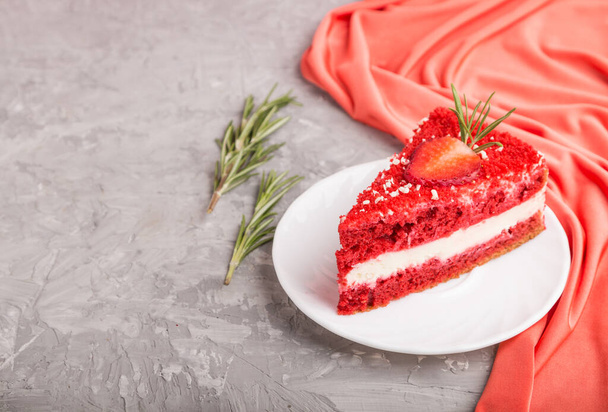 Σπιτικό κόκκινο βελούδινο κέικ με κρέμα γάλακτος και φράουλα σε γκρι φόντο τσιμέντου με κόκκινο ύφασμα. πλαϊνή όψη, χώρος αντιγραφής, επιλεκτική εστίαση. - Φωτογραφία, εικόνα