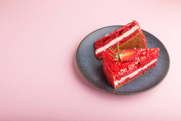 Homemade red velvet cake with milk cream and strawberry on blue ceramic plate on a pink pastel background. side view, copy space. - Фото, зображення