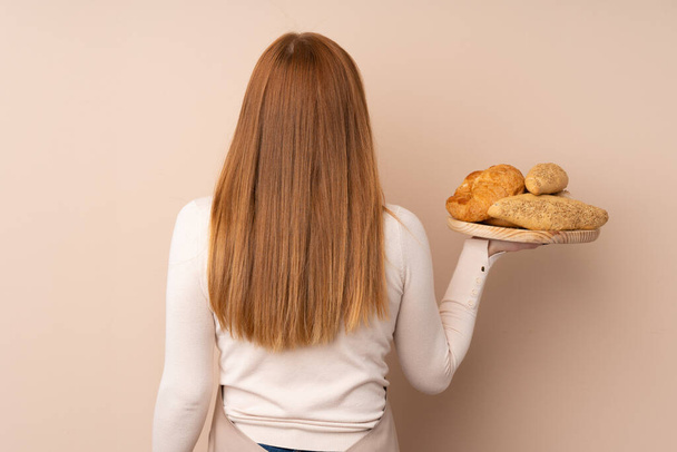 シェフの制服を着た若い赤毛の女性。女性のパン屋のテーブルにパンが数個置いてあります。 - 写真・画像