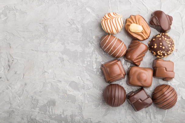 Diferentes caramelos de chocolate sobre un fondo de hormigón gris. vista superior, plano, espacio para copiar. - Foto, Imagen