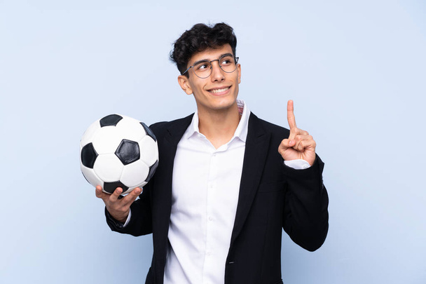 Argentinischer Fußballtrainer vor isoliertem blauen Hintergrund, der die Lösung erkennen will, während er den Finger hebt - Foto, Bild