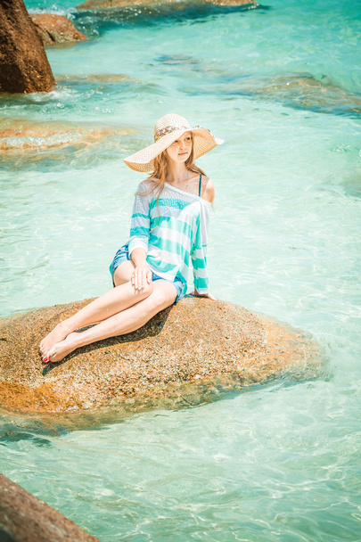 Woman relaxing on a stone in blue ocean - Фото, изображение