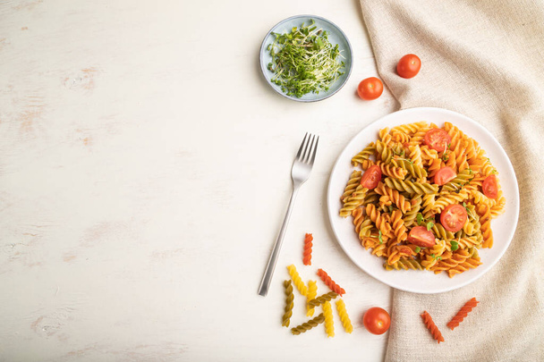 Tortiglioni semolina pasta met tomaat en microgroene spruiten op een witte houten ondergrond en linnen textiel. Bovenaanzicht, flat lay, kopieerruimte. - Foto, afbeelding