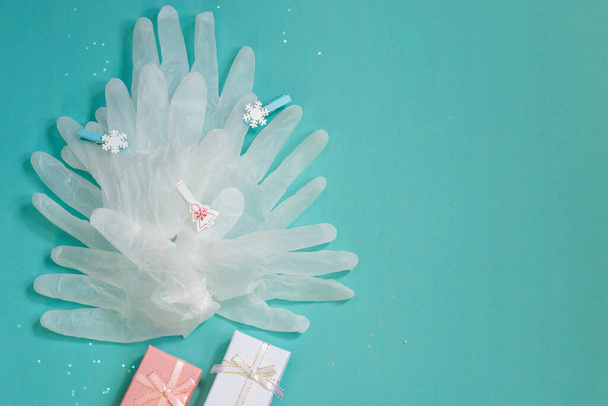Medizinische Einweg-Schutzhandschuhe für Hände, die einen Weihnachtsbaum auf blauem Hintergrund formen. Weihnachten und medizinisches Happy New Year Konzept. Ansicht von oben. Kopierraum. - Foto, Bild