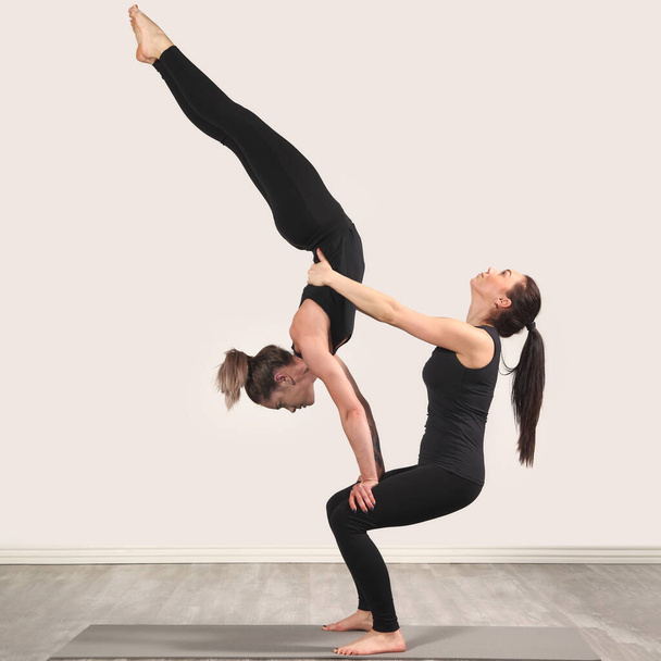 Two slim woman are doing yoga indoors - Photo, Image