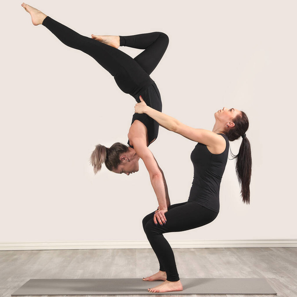 Two slim woman are doing yoga indoors - Foto, Imagen