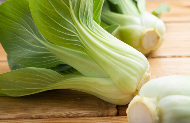 Fresh green bok choy or pac choi chinese cabbage on a brown wooden background. Side view, close up. - Photo, Image
