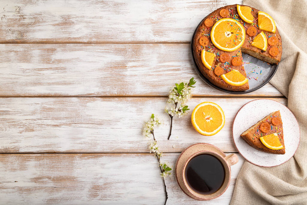 Апельсиновый торт и чашка кофе на белом деревянном фоне и льняной ткани. Вид сверху, плоский, копировальное пространство. - Фото, изображение