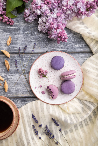 Purple macarons or macaroons cakes with cup of coffee on a gray wooden background and white linen textile. Top view, flat lay, close up. - Foto, Bild