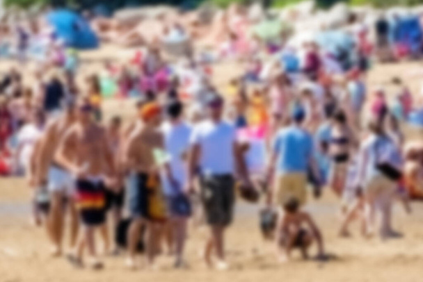Blue of people at a beach. It is bright, sunny day, most people wear swimsuits. Lots or people, but none recognizable due to blur. - Photo, Image