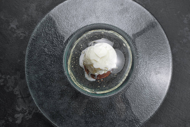 Fondant de chocolate con helado, sobre un plato transparente, sobre un fondo negro - Foto, imagen