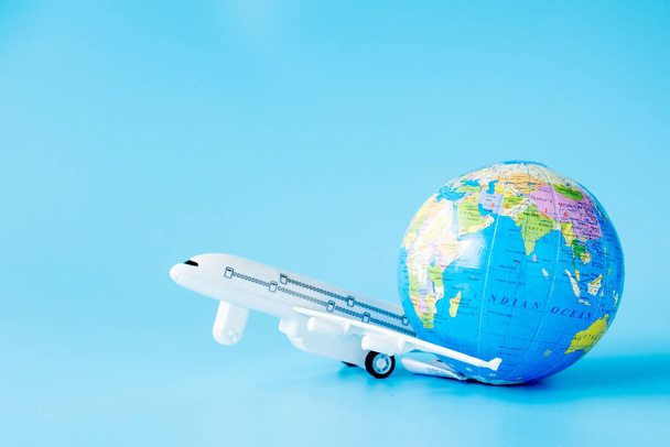 Airplane and globe on blue background. Summer or vacation concept. Copy space. - Foto, Imagen