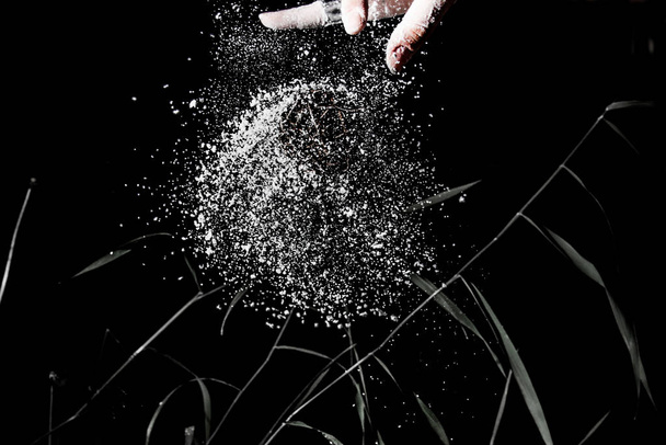A hand throwing a ball made of branches and splashes of flour - Φωτογραφία, εικόνα