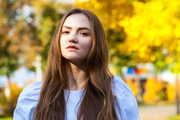 Close up portrait of a young beautiful brunette woman in autumn park - Fotó, kép