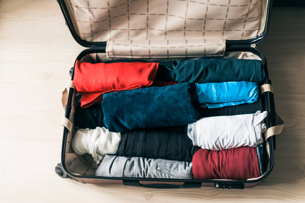 Packing luggage for a new journey. Suitcase with things on the wooden floor - 写真・画像
