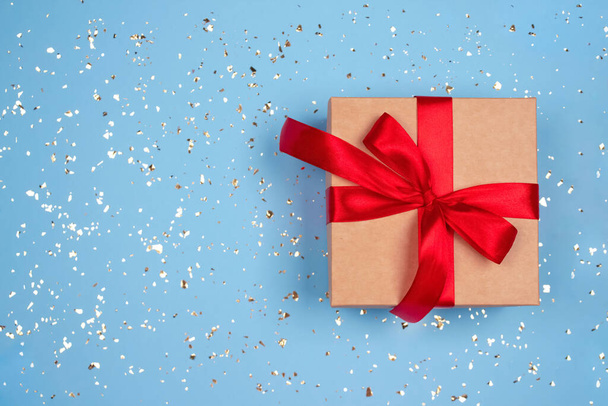 あなたのテキストの周りに黄金の輝きとコピースペースとお祝いの青の背景に赤い弓と現在のボックス。フラットレイアウトスタイル。クリスマス、新年、バレンタインデー、誕生日のお祝いのコンセプト - 写真・画像