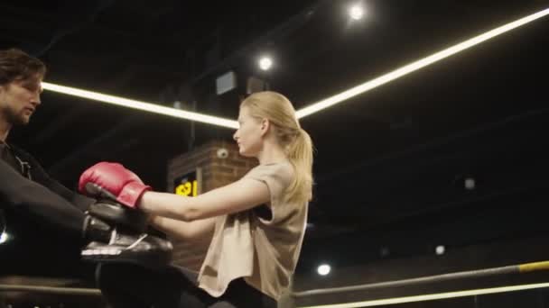 Взволнованная спортсменка практикует удары ногами по боксерскому рингу. Фитнес девушки бокс в спортзале - Кадры, видео