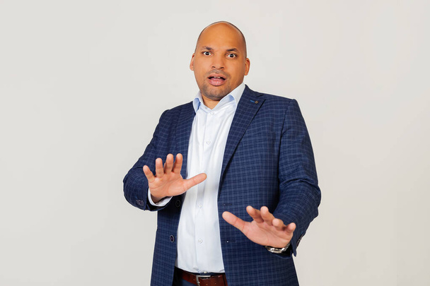 Portrait of shocked young African American businessman guy, scared and frightened by fear expression, stopped hand gesture, shouting in shock. Panic concept. Standing on a gray background. - 写真・画像