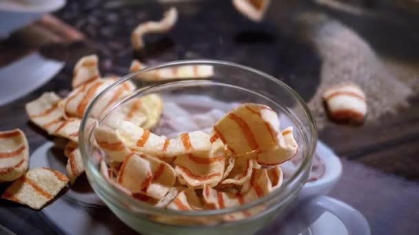Appetitlich gelb gebratene Kartoffelchips mit Speck fallen in Glasschale auf den Tisch - Filmmaterial, Video