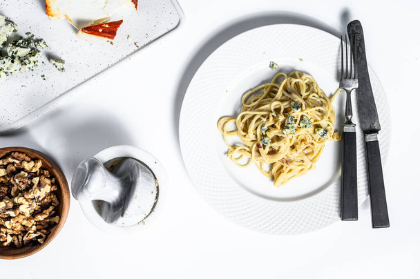 Pasta de espaguetis con salsa de queso azul crema y nueces. Comida casera italiana. Concepto para un sabroso plato vegetariano. Fondo blanco. Vista superior. - Foto, Imagen