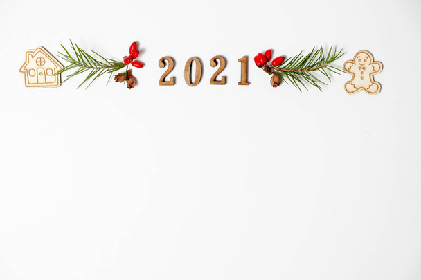 Χριστουγεννιάτικο πλαίσιο, διακοσμητικό περίγραμμα. Χειμερινή σύνθεση των αριθμών 2021, έλατα κλαδιά, κόκκινα μούρα. Επίπεδη lay και αντίγραφο χώρου. - Φωτογραφία, εικόνα