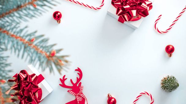 Świąteczny prezent. Białe prezenty ze szkarłatnym łukiem, czerwone kulki i drzewo zimowe w dekoracji xmas na białym tle dla kartki okolicznościowej. Świąteczne tło z miejscem na tekst - Zdjęcie, obraz
