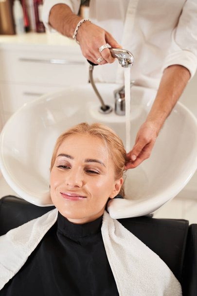 Hairdresser washing hair - Фото, изображение