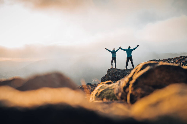 Pari matkustajat Mies ja nainen seisoo kalliolla rentouttava vuoret ja pilvet antenni näkymä Rakkaus ja matka onnellisia tunteita elämäntapa käsite. Nuori perhe matkustaa aktiivinen seikkailu lomat - Valokuva, kuva
