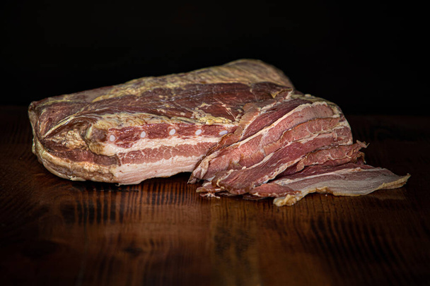 Κομμάτι από μεγάλο φέτες ζαμπόν κρέατος στο ξύλο - Φωτογραφία, εικόνα