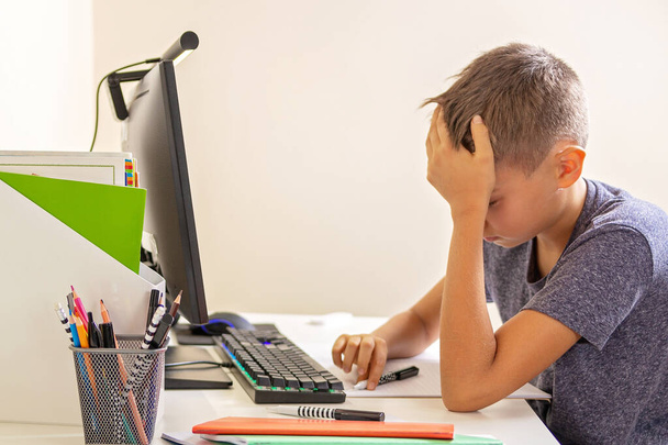 Kid with computer doing homework at home. Learning difficulties, online learning, education concept - 写真・画像