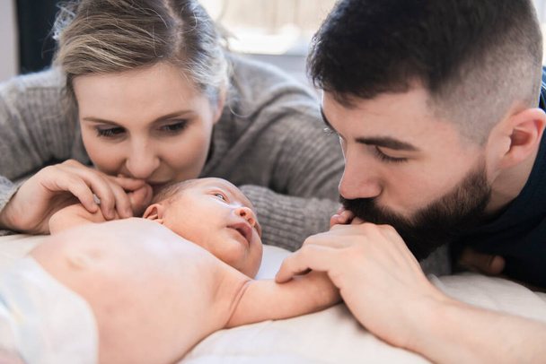 family lay on bed with his newborn baby daughter - Foto, Imagen