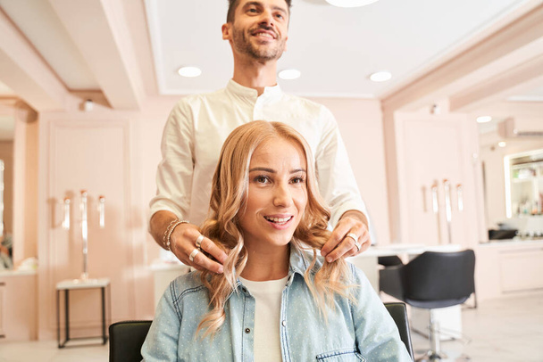 Hairdresser styling the hair of a customer - Фото, зображення