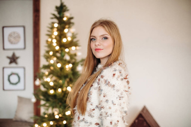 Krásná mladá žena pózuje v blízkosti vánočního stromu - Fotografie, Obrázek