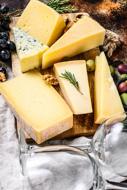 Verschiedene Käsesorten, Oliven und Rosmarin. Verschiedene leckere Snacks. Dunkler Hintergrund. Ansicht von oben. - Foto, Bild