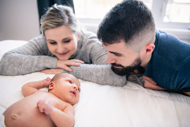 family lay on bed with his newborn baby daughter - Foto, immagini