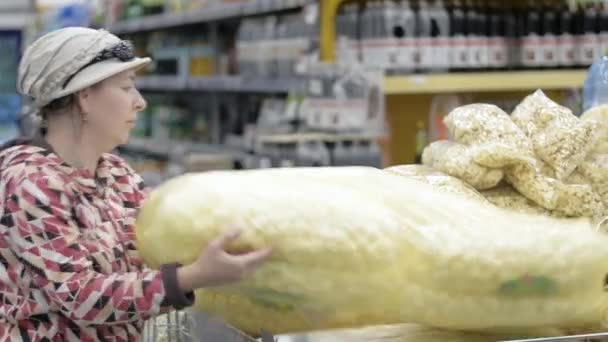 Μια γυναίκα σε ένα κατάστημα αγοράζει μια μεγάλη σακούλα κορν φλέικς.. - Πλάνα, βίντεο