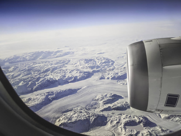 Ein Blick aus einem Flugzeugfenster auf Himmel und arktisches Grönland und Ozean. Schnee, Eisberg. - Foto, Bild