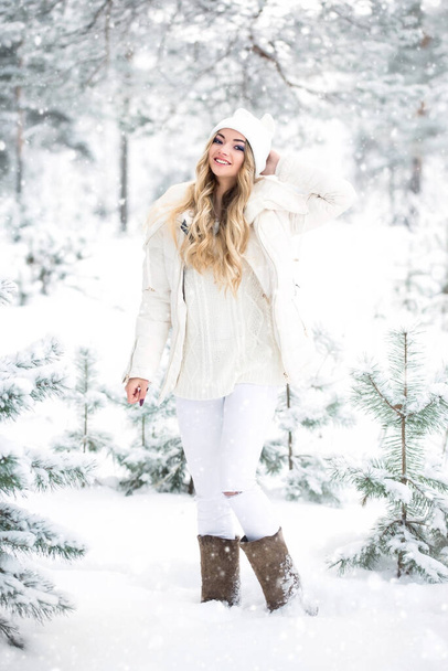 Smiling young woman in winter clothes in a snowy forest walking in felt boots. - Foto, imagen